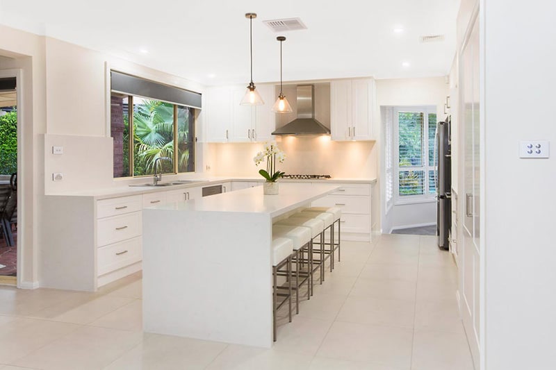 19.classic white hampton style kitchen with caesarstone benchtop and canopy rangehood, island with breakfast bar